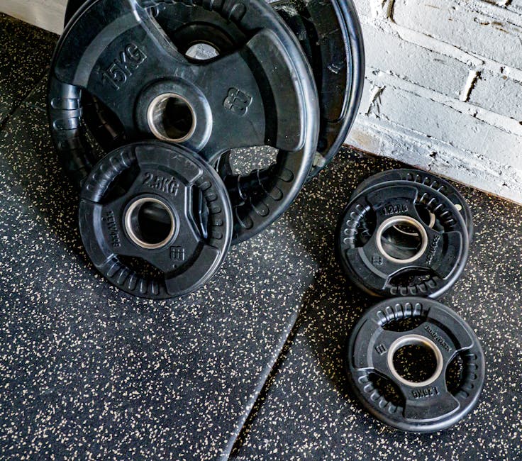 Close-up view of stacked weight plates in a gym environment against a textured wall.