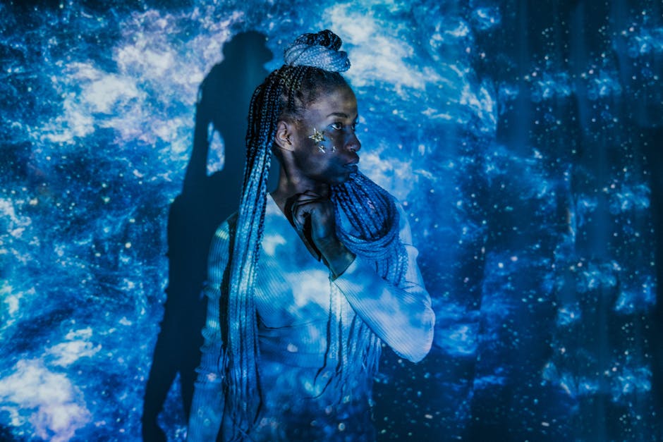 Captivating studio portrait of a woman with braided hair, enveloped in a cosmic light projection, creating a mystical ambiance.