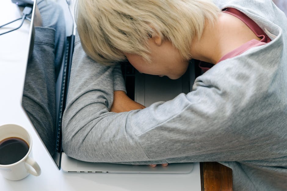 Tired woman resting her head on a laptop, symbolizing work fatigue and burnout.