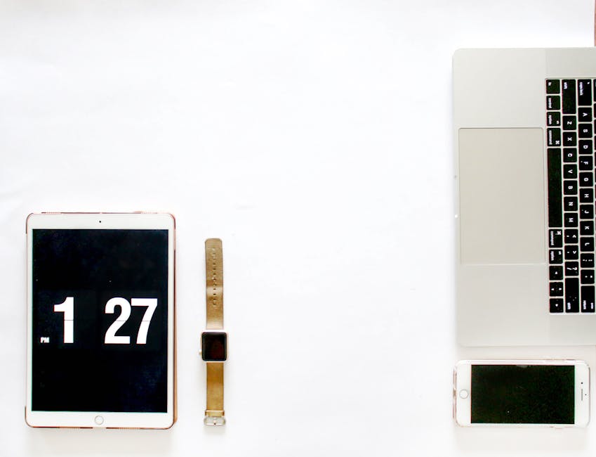 Modern minimalist flat lay featuring a laptop, smartphone, tablet, and smartwatch on a white background.