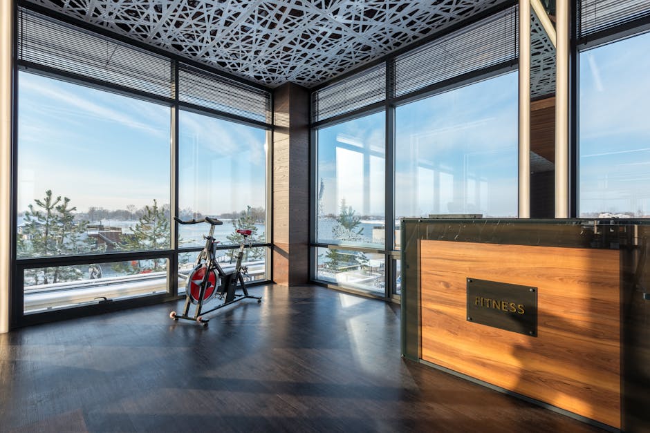 Spacious modern gym featuring an exercise bike with large windows showcasing a scenic outdoor view.