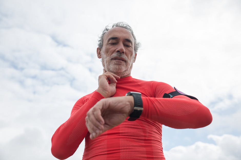 Elderly man in red active wear checking wristwatch outdoors under cloudy sky.